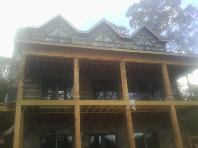 Dormers and porch framing on a large log home under construction — Roof Coating work by our crew in Buckley
