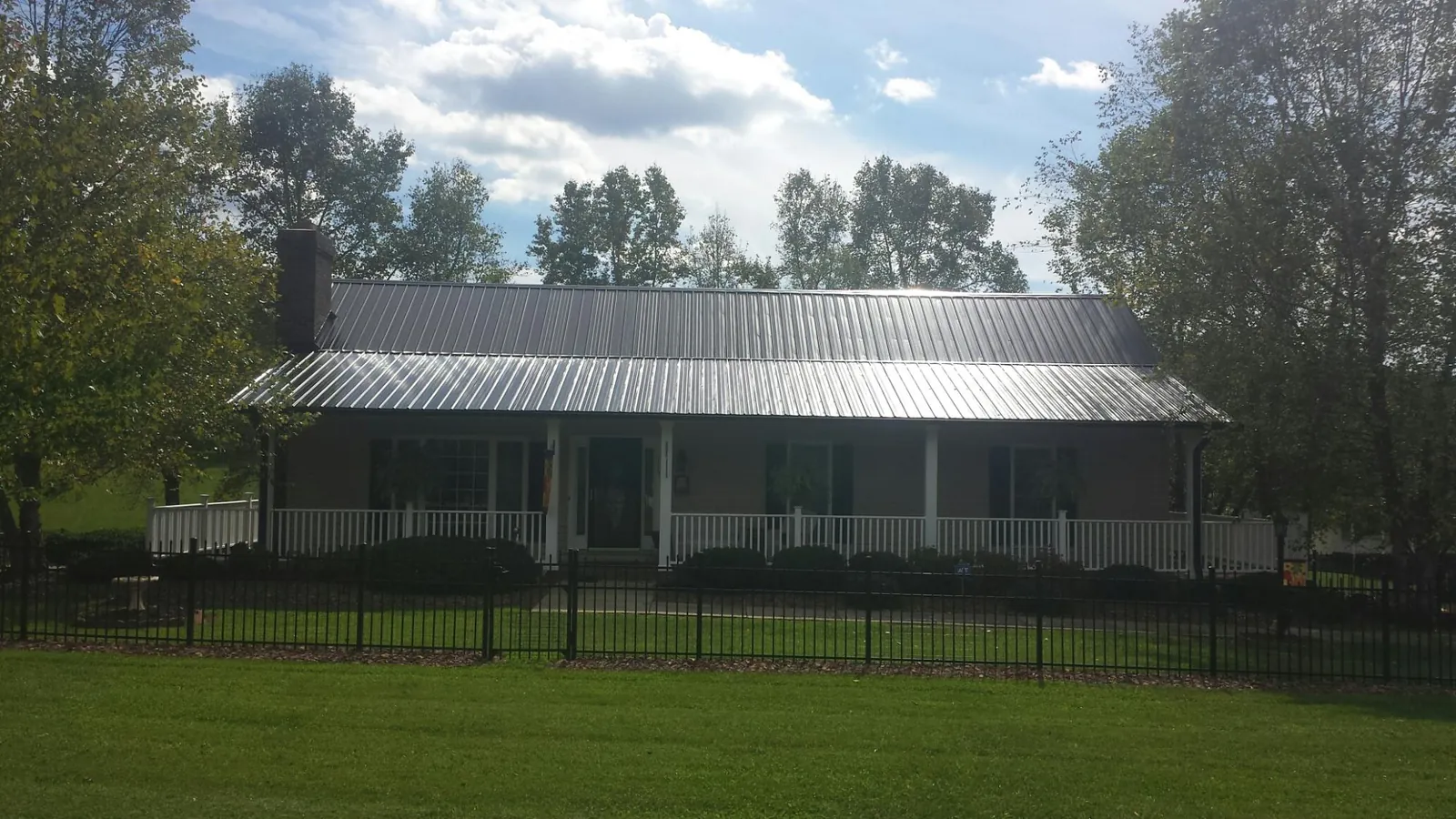 Gray metal roof on a brick ranch with a full width front porch — Gutter Guard Installation work by our crew in Buckley