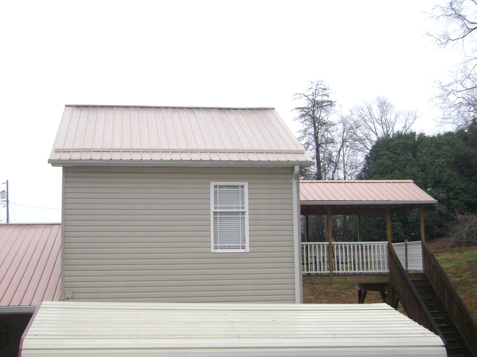 Tan metal roofs on a two story addition and attached porch, from a Roof Replacement job in Buckley