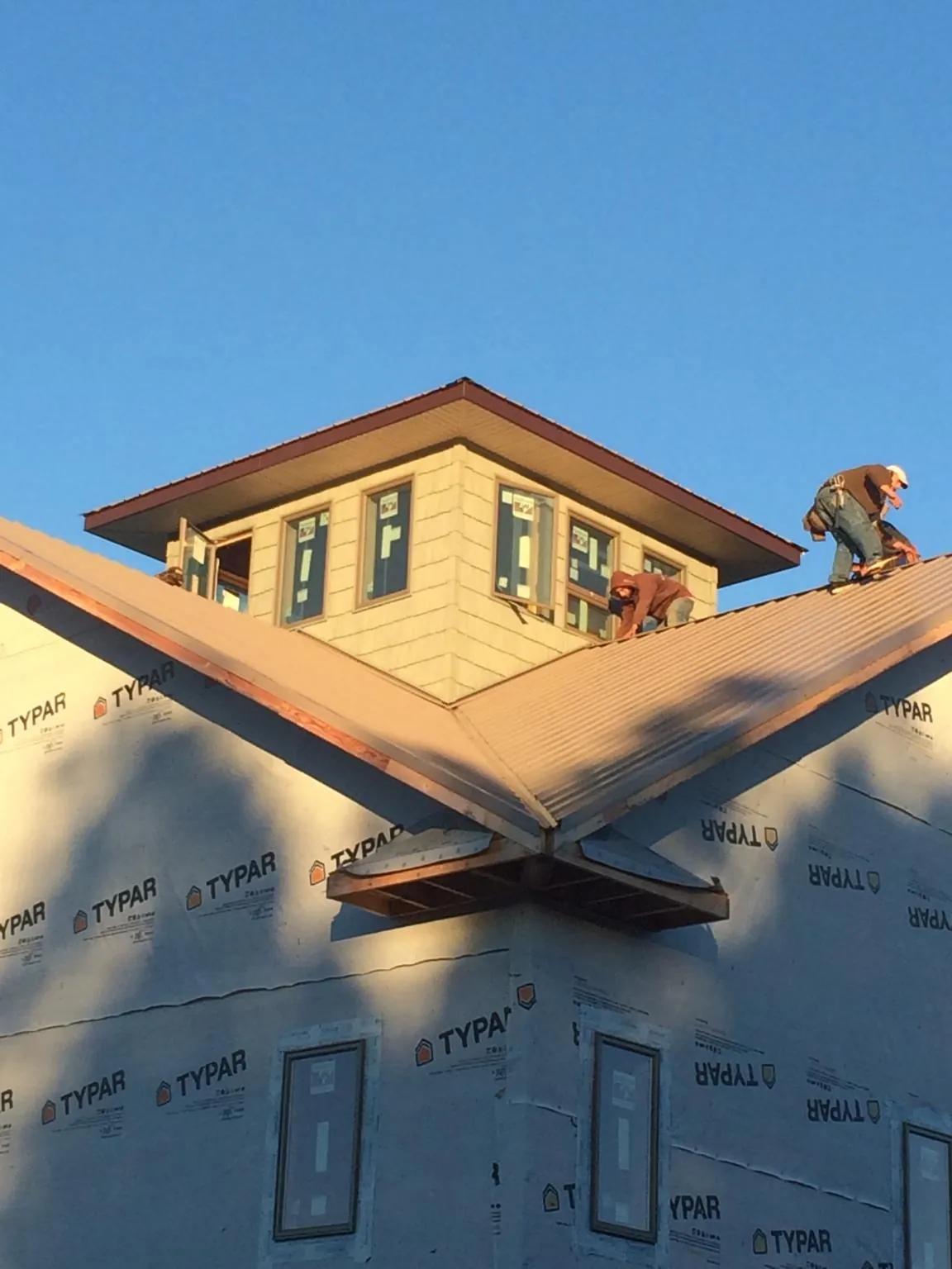 Roofers working around a rooftop cupola on a new metal roof at sunset — Roof Waterproofing in Buckley by Roofing Brothers